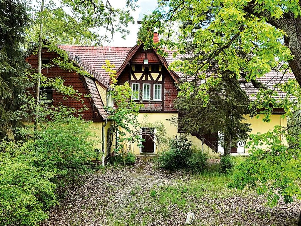 Fachwerkgiebel des Forsthauses in sattem Sommergrün mit gelb verputzter Fassade