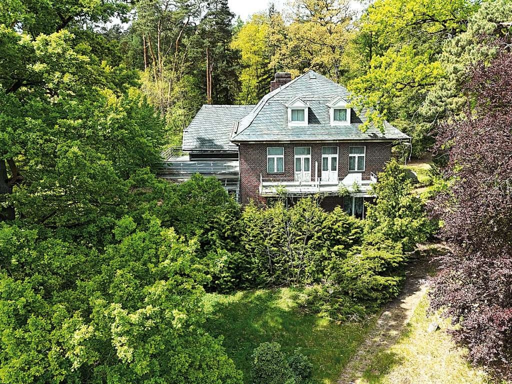 Luftaufnahme der Seevilla im Sommergrün, Backsteinfassade mit Gauben und Balkon
