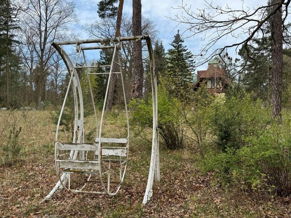 Alte Sesselschaukel im Garten, im Hintergrund die Seevilla